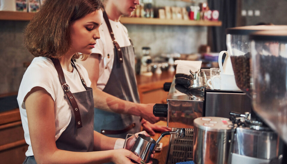Ekstrajobb som krever mer enn ti timer per uke, går ut over tid brukt på studier. Ung, kvinnelig student lager kaffe på en kaffebar.